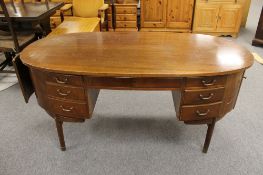 A mid 20th century oval walnut writing desk fitted seven drawers and cabinets either side