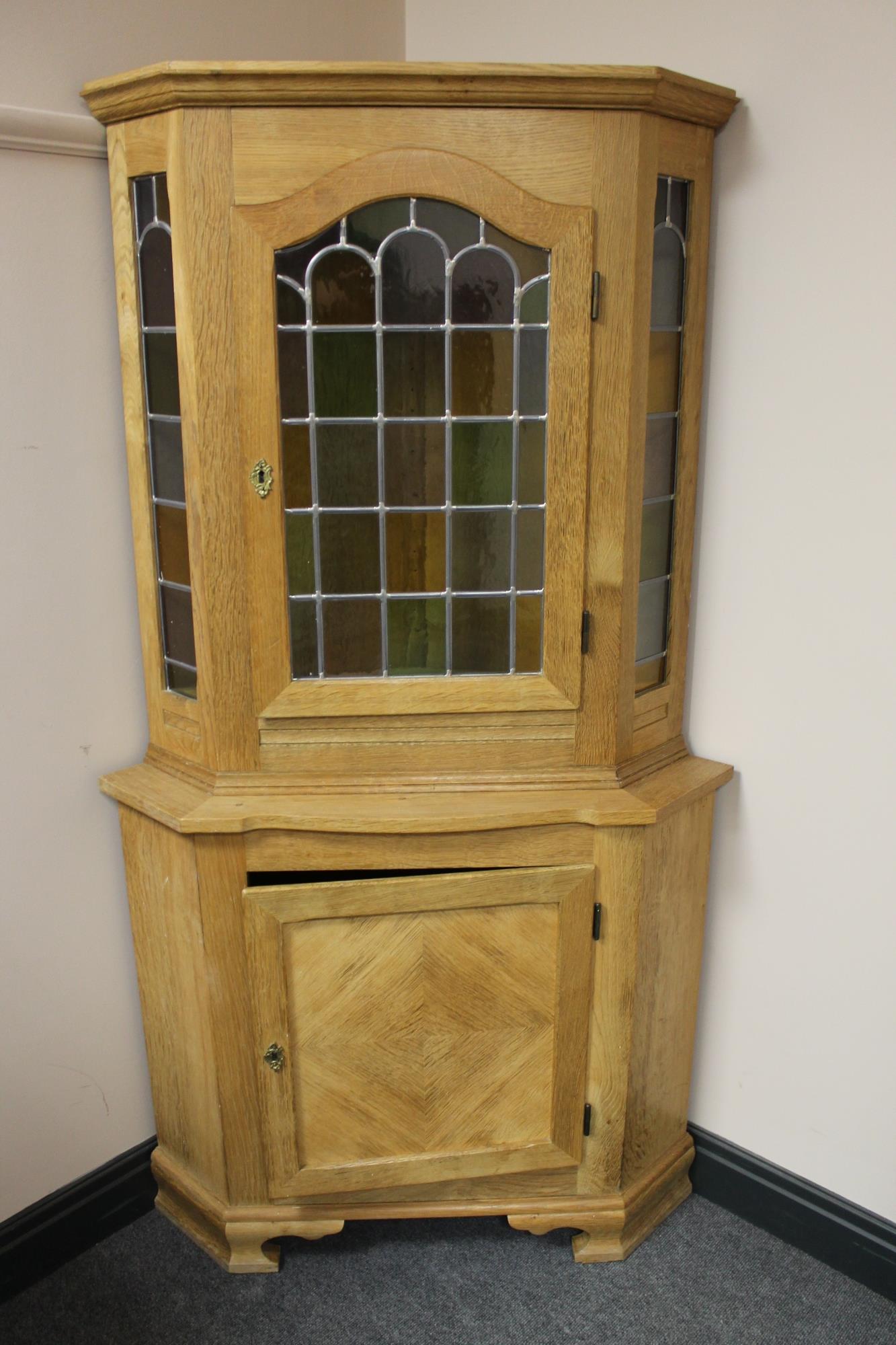 A blonde oak corner cabinet