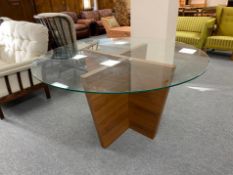 A contemporary circular plate glass top dining table on walnut effect base