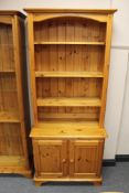 A set of pine open shelves fitted double door cupboard