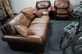 A brown leather three piece lounge suite and brown leather cushions