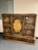 A carved oak triple door sideboard fitted three drawers beneath