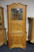 A blonde oak corner cabinet (glass a/f)