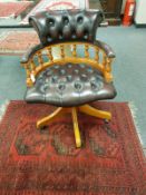 A reproduction captain's armchair in brown button leather,