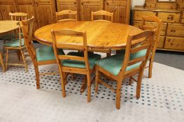 A circular pine extending pedestal table and six ladder back chairs