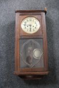 An early 20th century oak cased wall clock with silvered dial pendulum and key