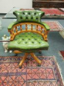 A reproduction captain's armchair in green button leather,