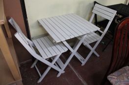 A folding wooden garden table with two chairs