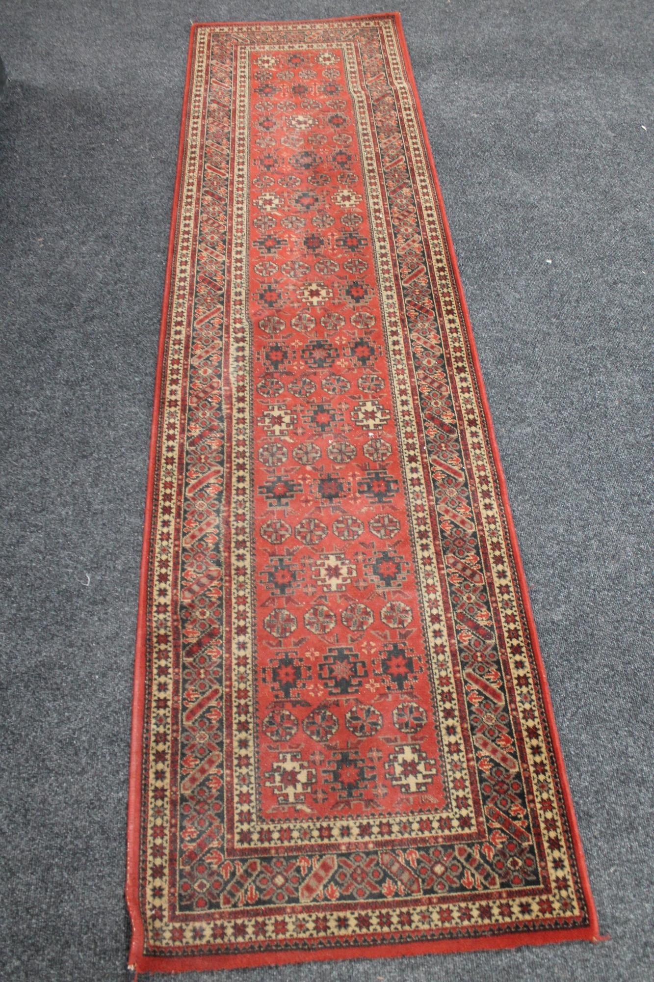 A woolen carpet runner on red ground CONDITION REPORT: 68 cm x 270 cm.