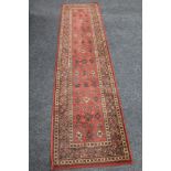 A woolen carpet runner on red ground CONDITION REPORT: 68 cm x 270 cm.