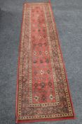 A woolen carpet runner on red ground CONDITION REPORT: 68 cm x 270 cm.