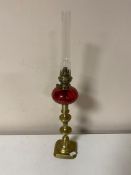 An antique Kosmos Brenner brass and cranberry glass oil lamp with chimney on brass base