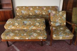 A mid century teak framed armchair in floral fabric together with a two-piece teak seating unit