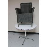 A circular cafe table on four-way metal base together with a wicker armchair