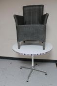 A circular cafe table on four-way metal base together with a wicker armchair