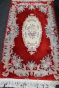 A fringed Chinese floral rug on red ground