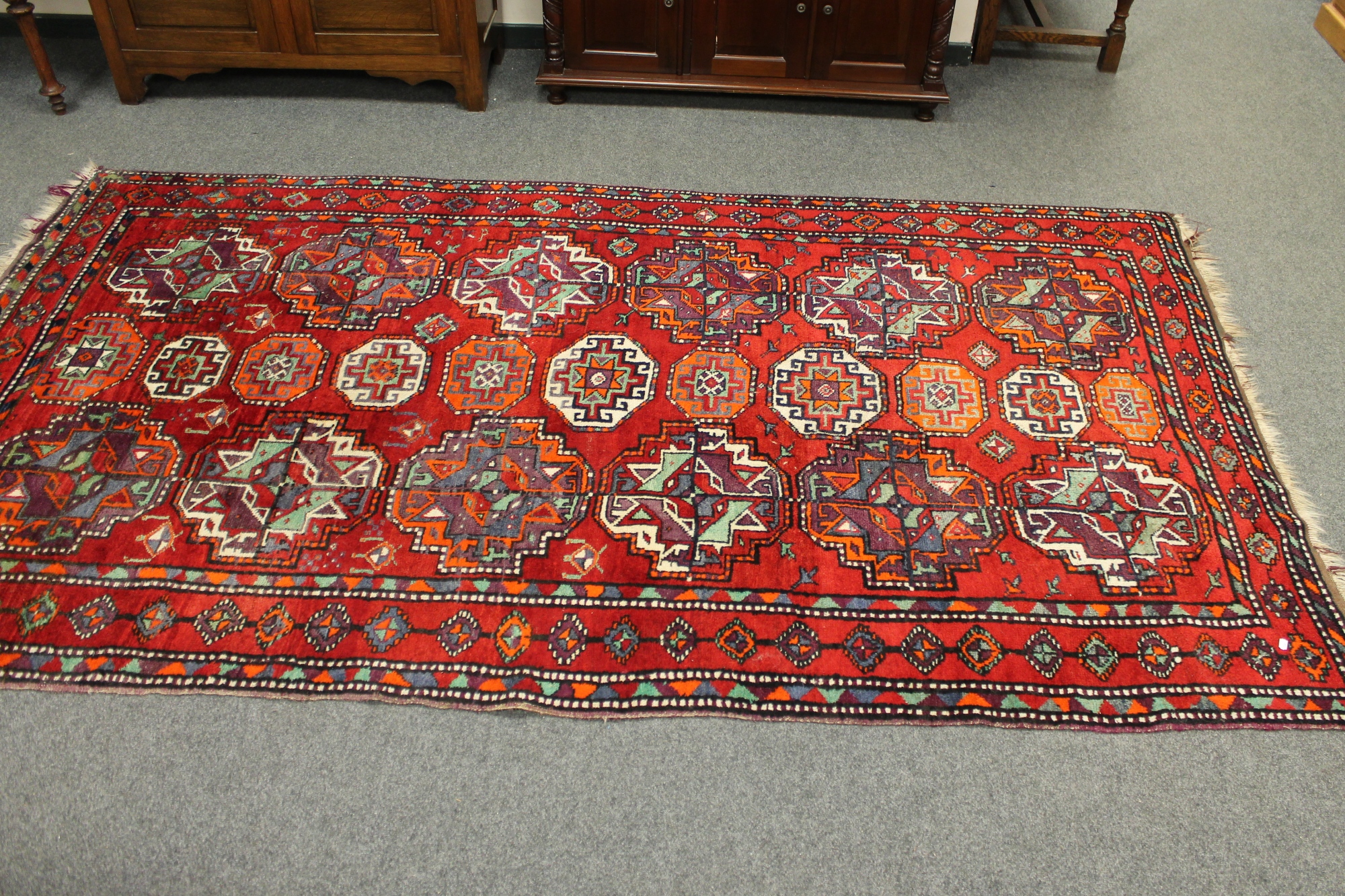 A Caucasian rug of geometric design on red ground,