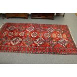 A Caucasian rug of geometric design on red ground,
