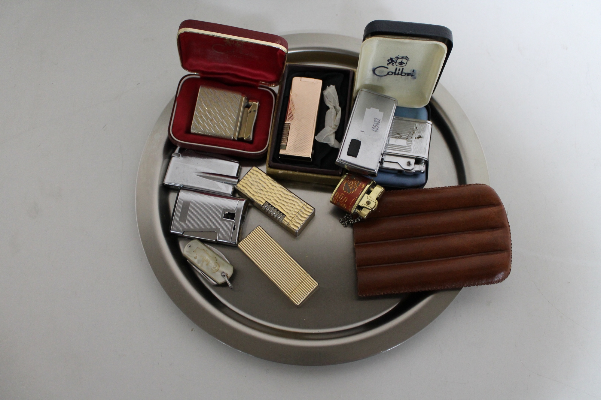A plated tray containing a collection of assorted gas lighters to include Calibri, Ronson,