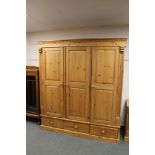 A good quality pine triple door wardrobe, fitted drawers below,