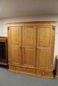 A good quality pine triple door wardrobe, fitted drawers below,