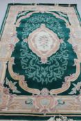 A Chinese fringed embossed rug on green ground