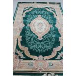 A Chinese fringed embossed rug on green ground