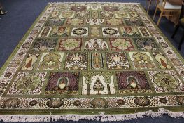 A machine made Persian design fringed carpet of compartmentalised design on green ground