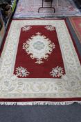 A fringed woolen carpet on red ground