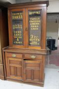 An Edwardian mahogany glazed door bookcase fitted with cupboards and drawers bearing haberdashery