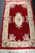 A fringed Chinese floral rug on red ground