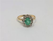 A 14ct yellow gold emerald and diamond cluster ring, the medium green emerald 7.