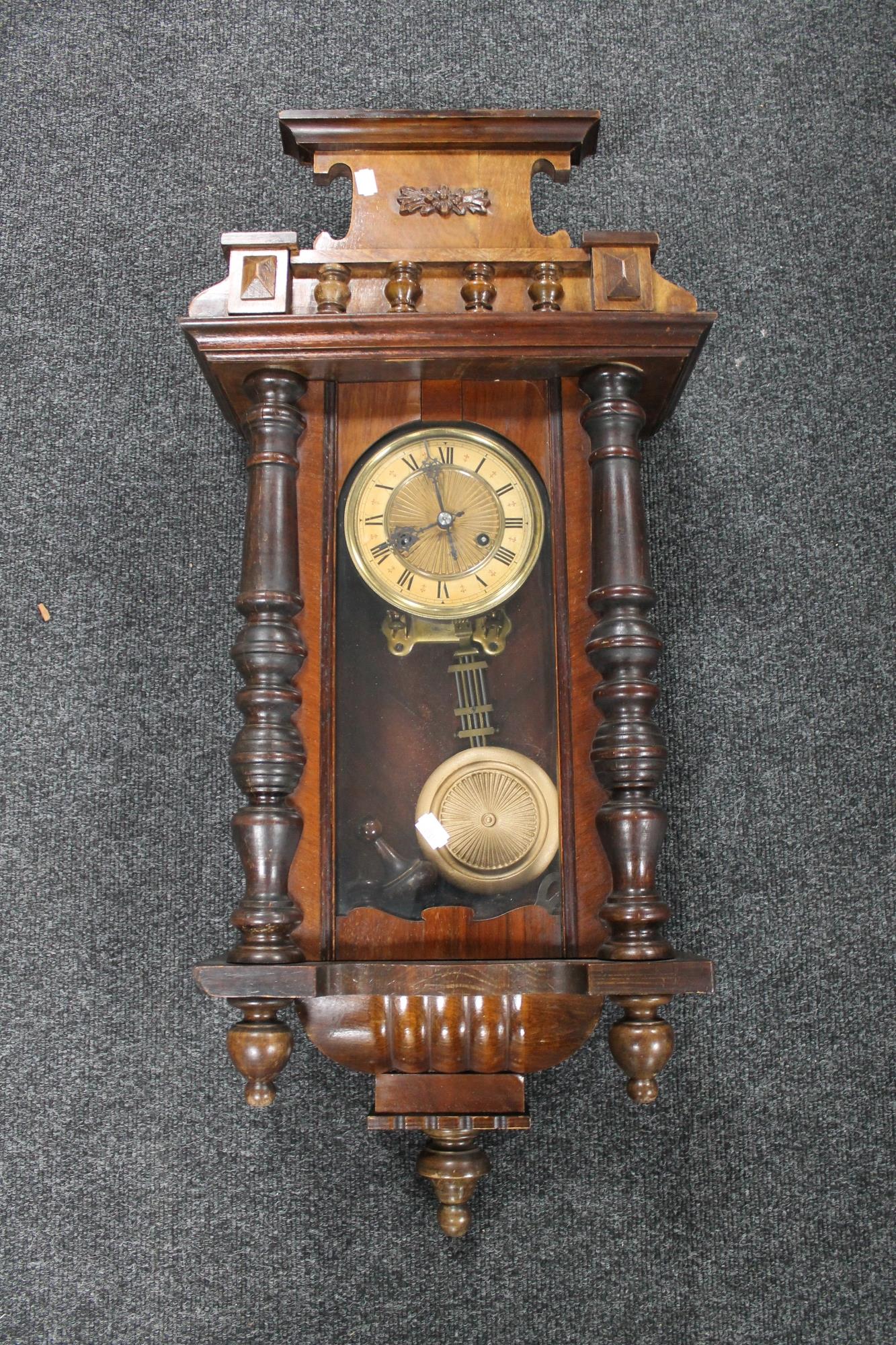 A Victorian stained beech wood wall clock with pendulum