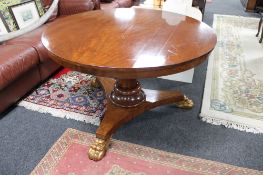 A Victorian circular breakfast table on three way pedestal with gilt lion paw feet