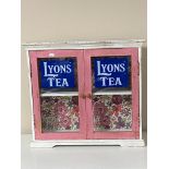 A painted double door wall cabinet bearing Lyon's Tea advertising