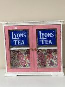 A painted double door wall cabinet bearing Lyon's Tea advertising