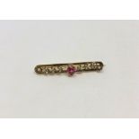 A 9ct gold seed pearl bar brooch set with a ruby coloured stone, 3.6g.