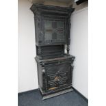 A late 19th century ebonised oak carved hunting cabinet with glazed leaded glass door