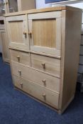 A light oak double door storage cabinet fitted with four drawers