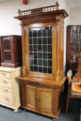 A continental walnut cabinet with leaded glass door