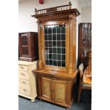 A continental walnut cabinet with leaded glass door