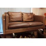 A 20th century Danish brown leather three seater and matching two seater settee