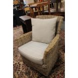 A pair of wicker armchairs with grey cushions