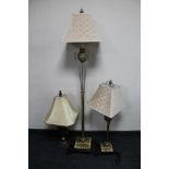 A silvered contemporary standard lamp together with two similar table lamps