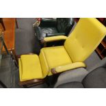 A contemporary armchair with matching footstool in yellow fabric