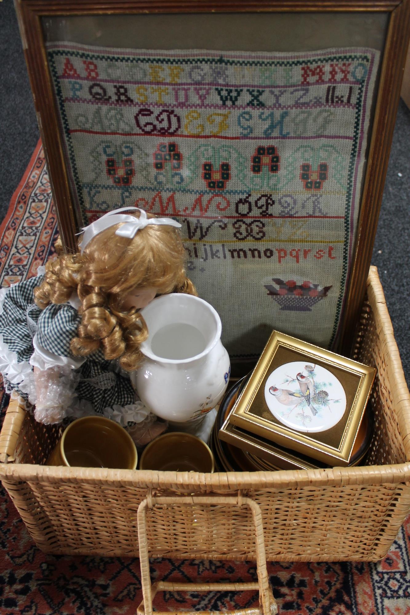 A wicker basket containing a tapestry sampler, Aynsley vase, ceramic plaques, doll,