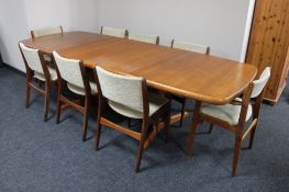 A mid 20th century teak extending dining room table with two leaves together with a set of eight