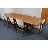 A mid 20th century teak extending dining room table with two leaves together with a set of eight