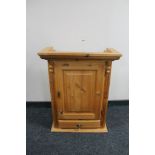 A pine wall cabinet fitted with a drawer