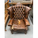 A distressed buttoned brown leather Chesterfield armchair